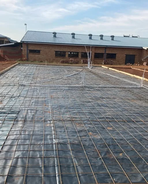 Reinforced surface bed ready for concrete in front of a face brick building